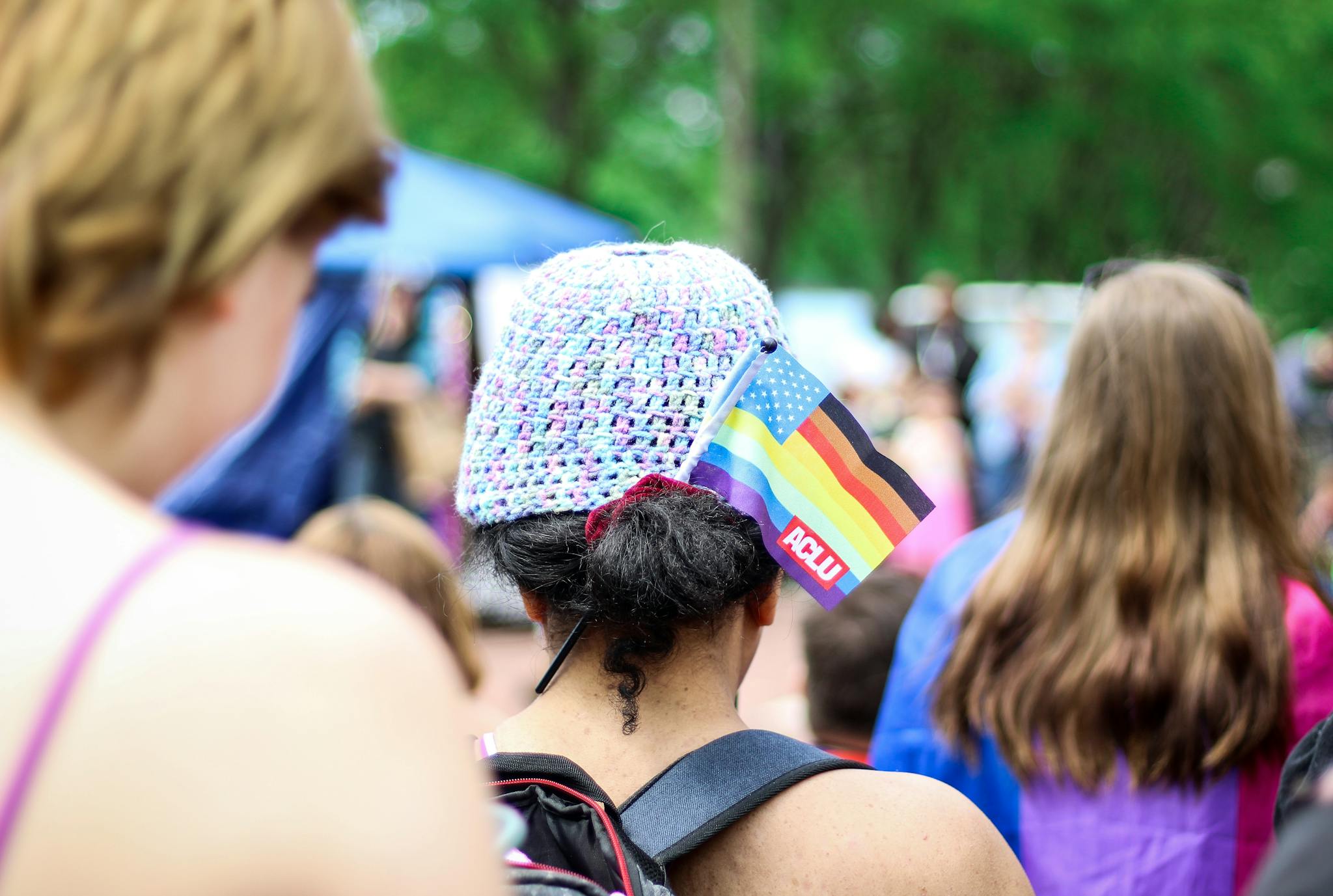 A colorful pride parade with people displaying diverse flags, celebrating LGBTQ+ pride outdoors.