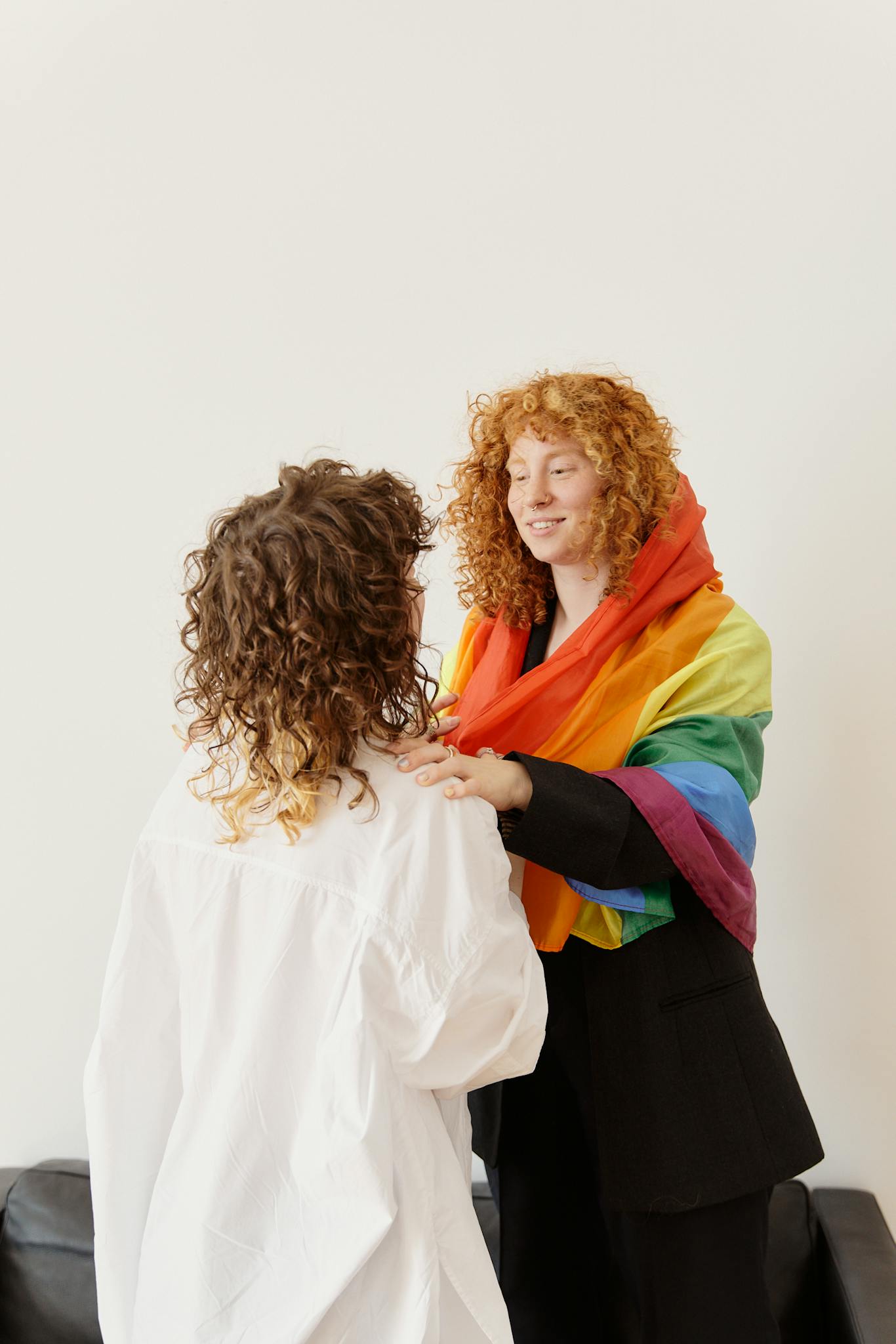 Two women embracing with a rainbow flag, representing LGBTQ pride and love.