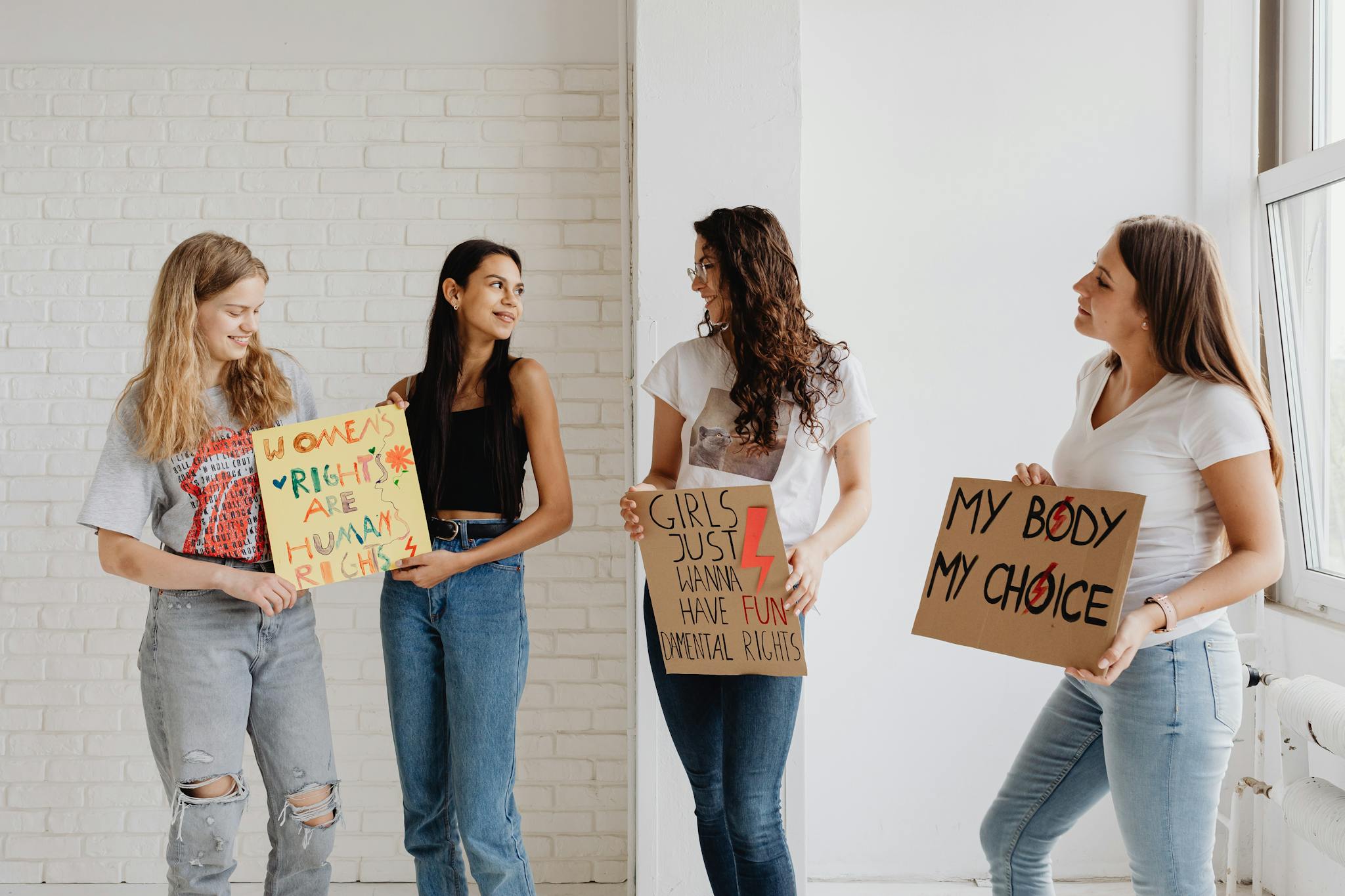 Women holding signs advocating for women's rights in a peaceful indoor setting.